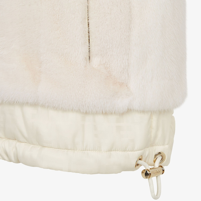 Short reversible vest with high collar and drawstring hem. One side has zipper pockets, the other hi 3